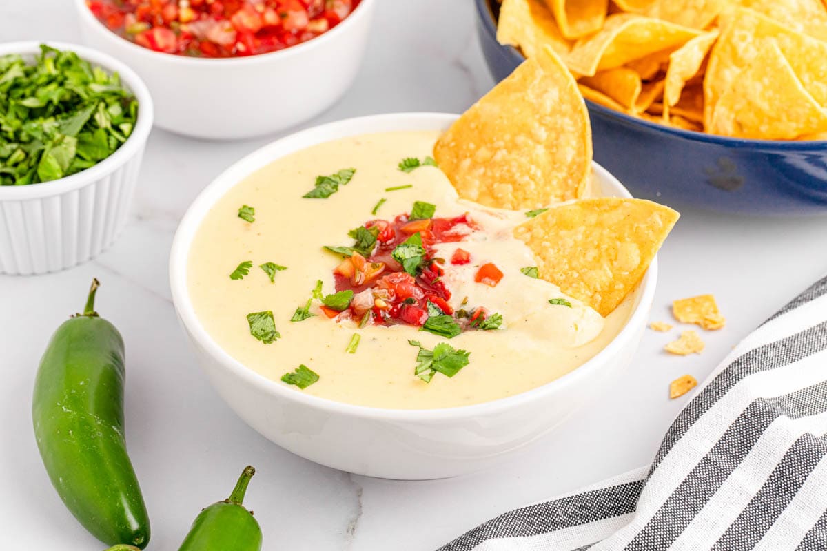 White queso dip in white bowl with chips