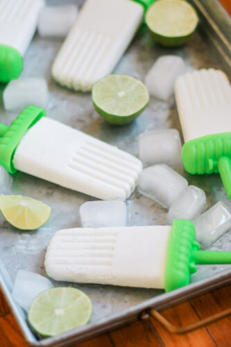Coconut lime popsicles on metal tray with ice