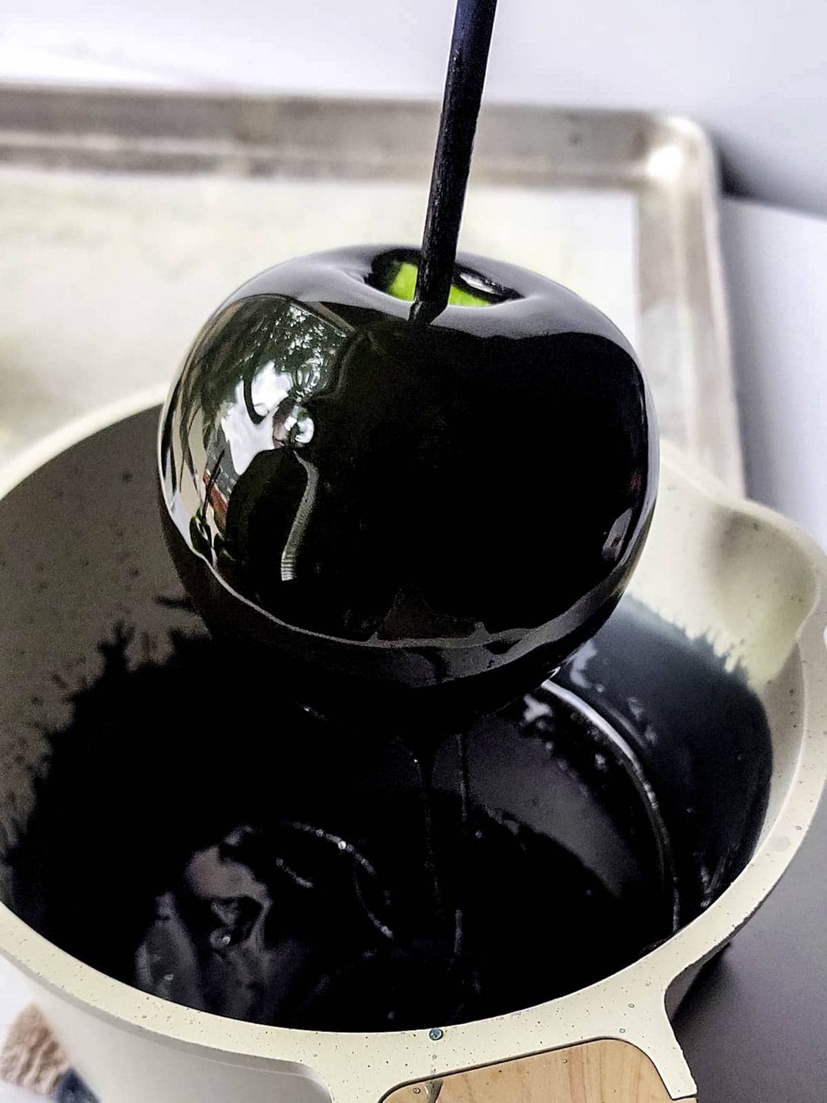 Dipping apple into black syrup mixture