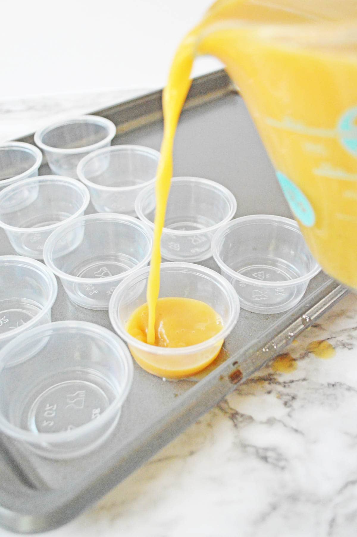 Pouring pumpkin jello shot mixture into plastic cups