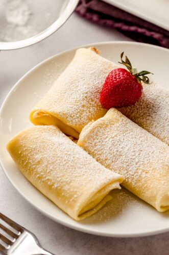 Cheese blintzes on plate with a strawberry