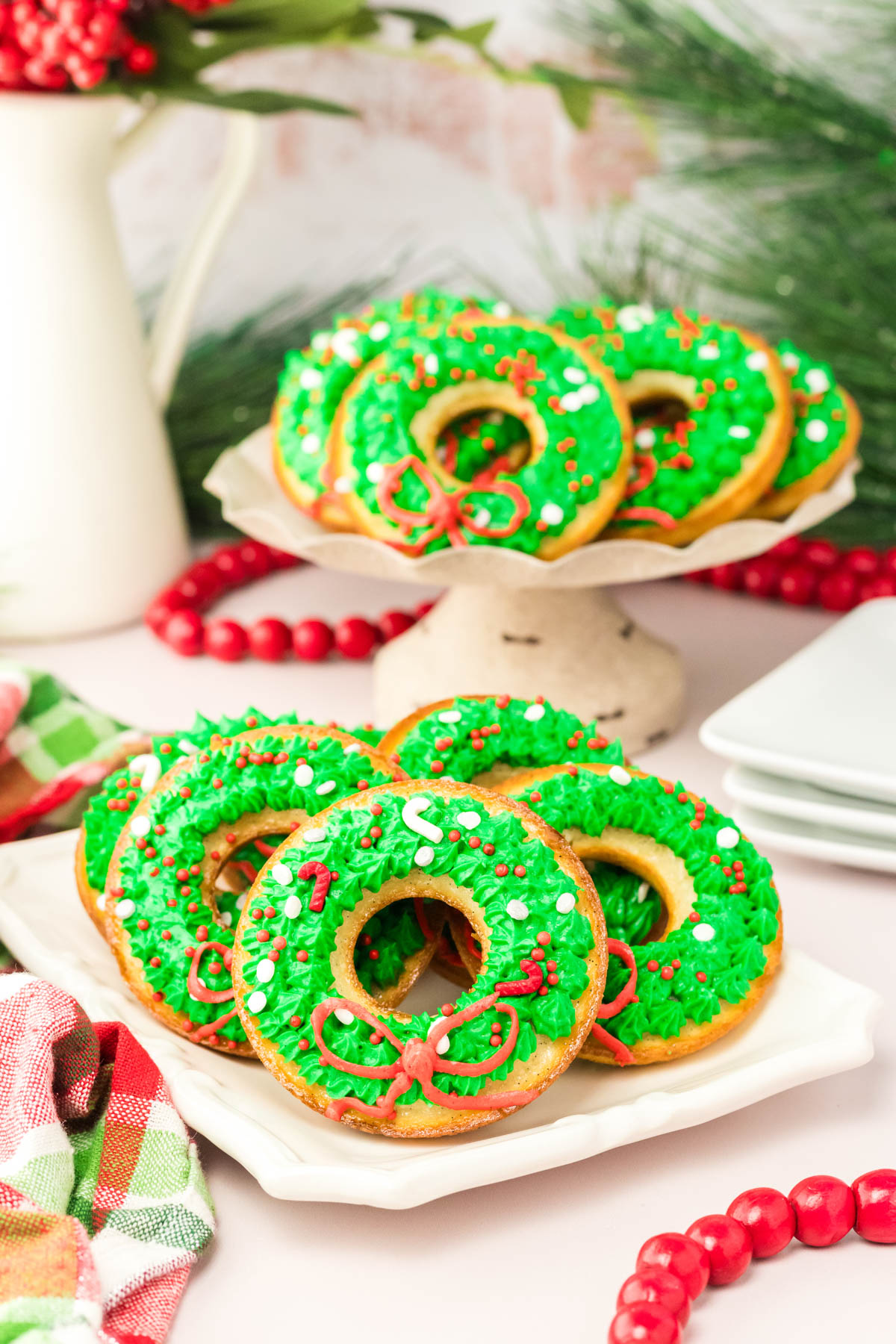 Donuts decorated with green and red icing on a white plate.