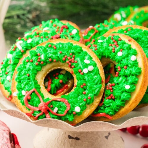 Donuts decorated with green and red icing on a plate.