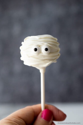 A person holding a white mummy cake pop.