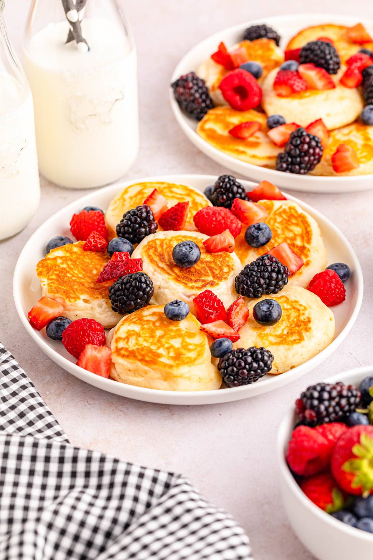 A plate of pancakes with berries and milk.