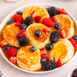 Pancakes with berries and syrup on a plate.