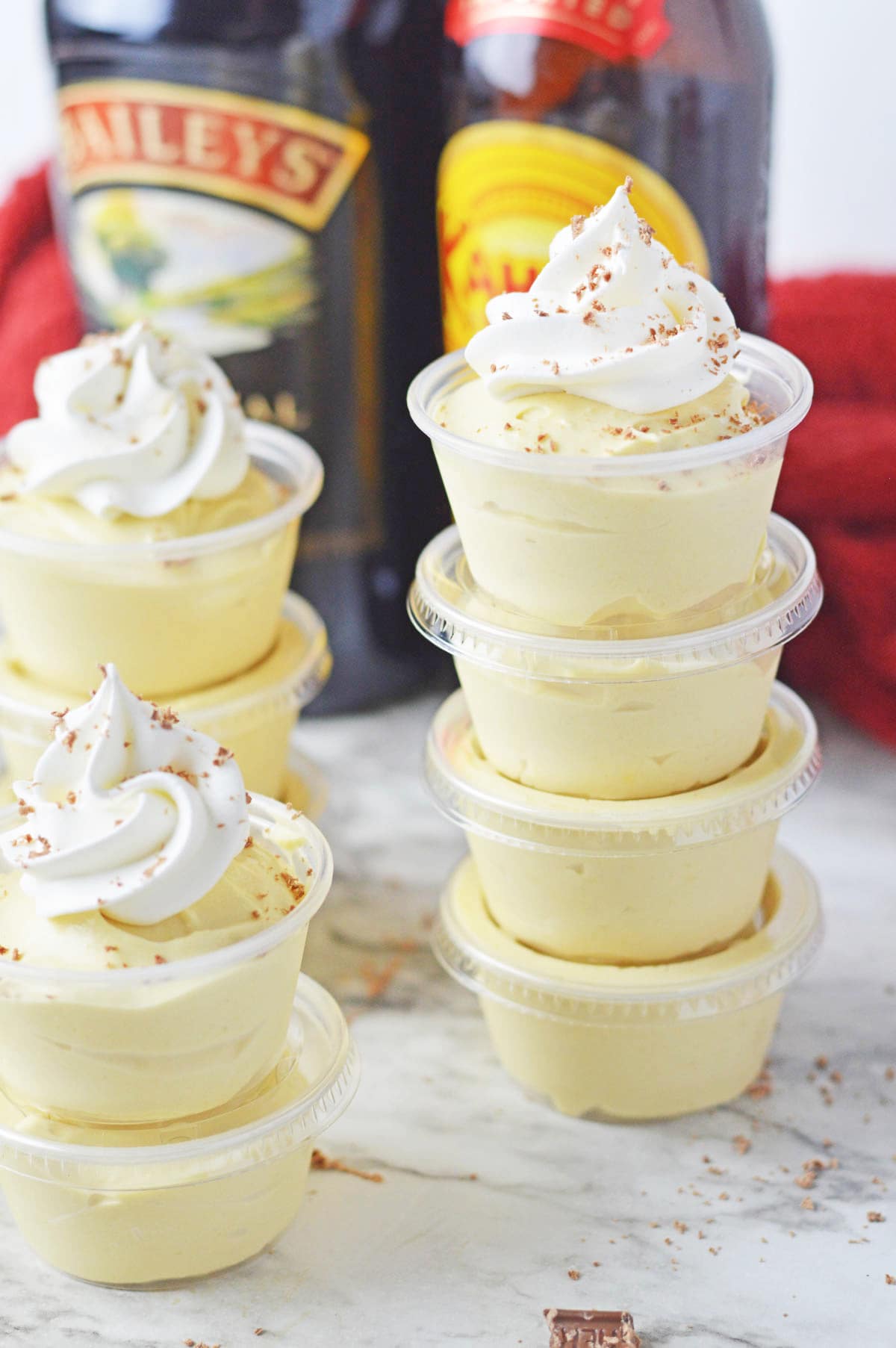 A group of dessert cups with whipped cream and a bottle of bailey's.