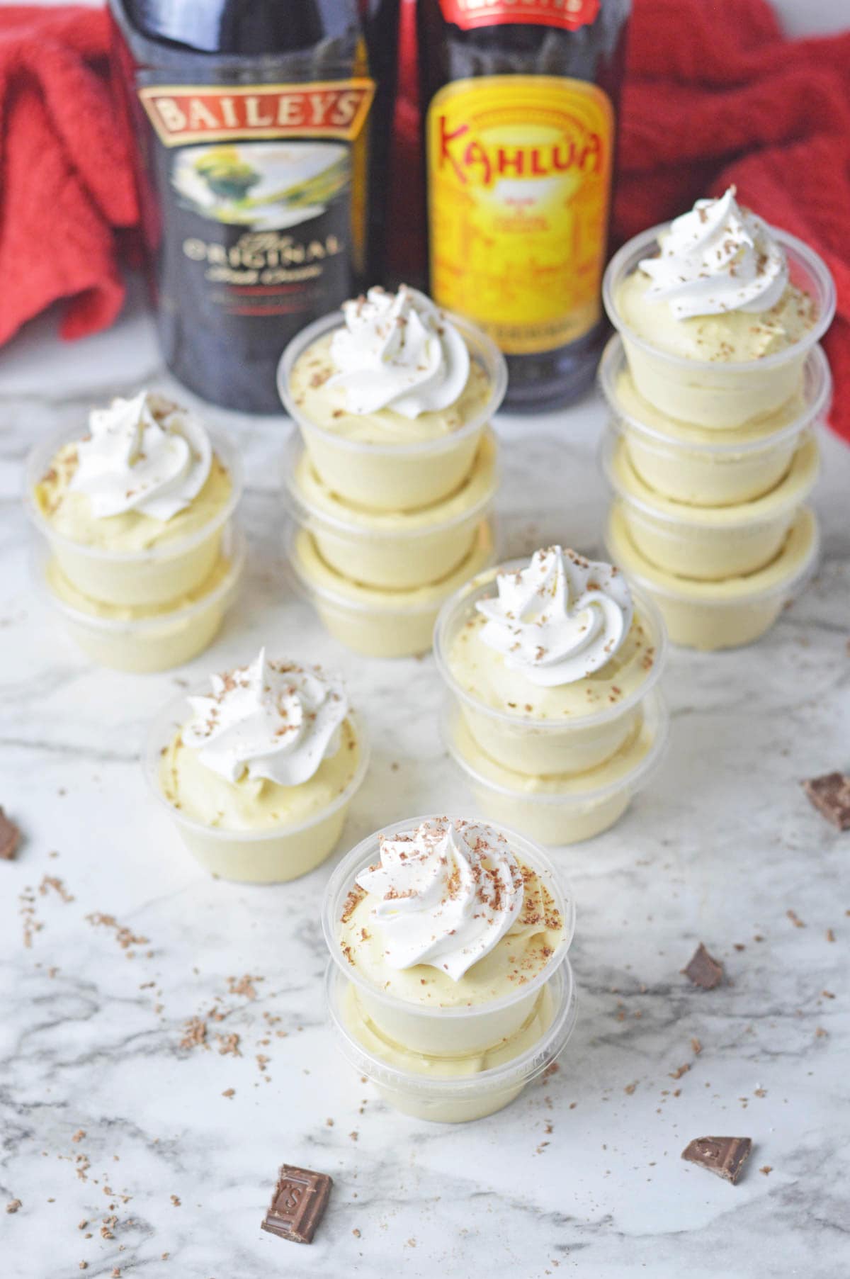 A group of dessert cups with whipped cream and a bottle of bourbon.