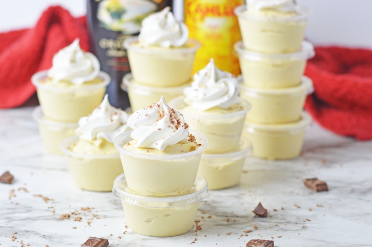 A group of dessert cups with whipped cream and a bottle of bourbon.