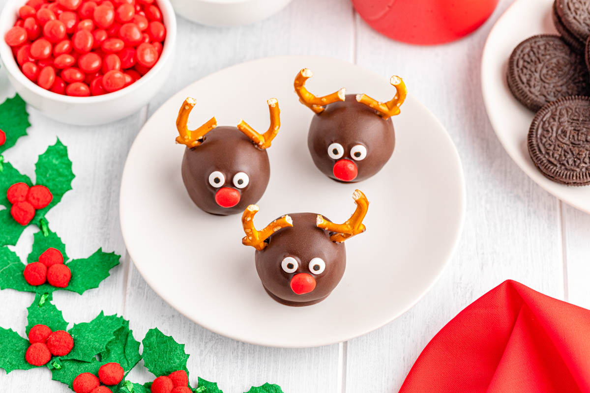 Three chocolate reindeer shaped truffles on a plate.