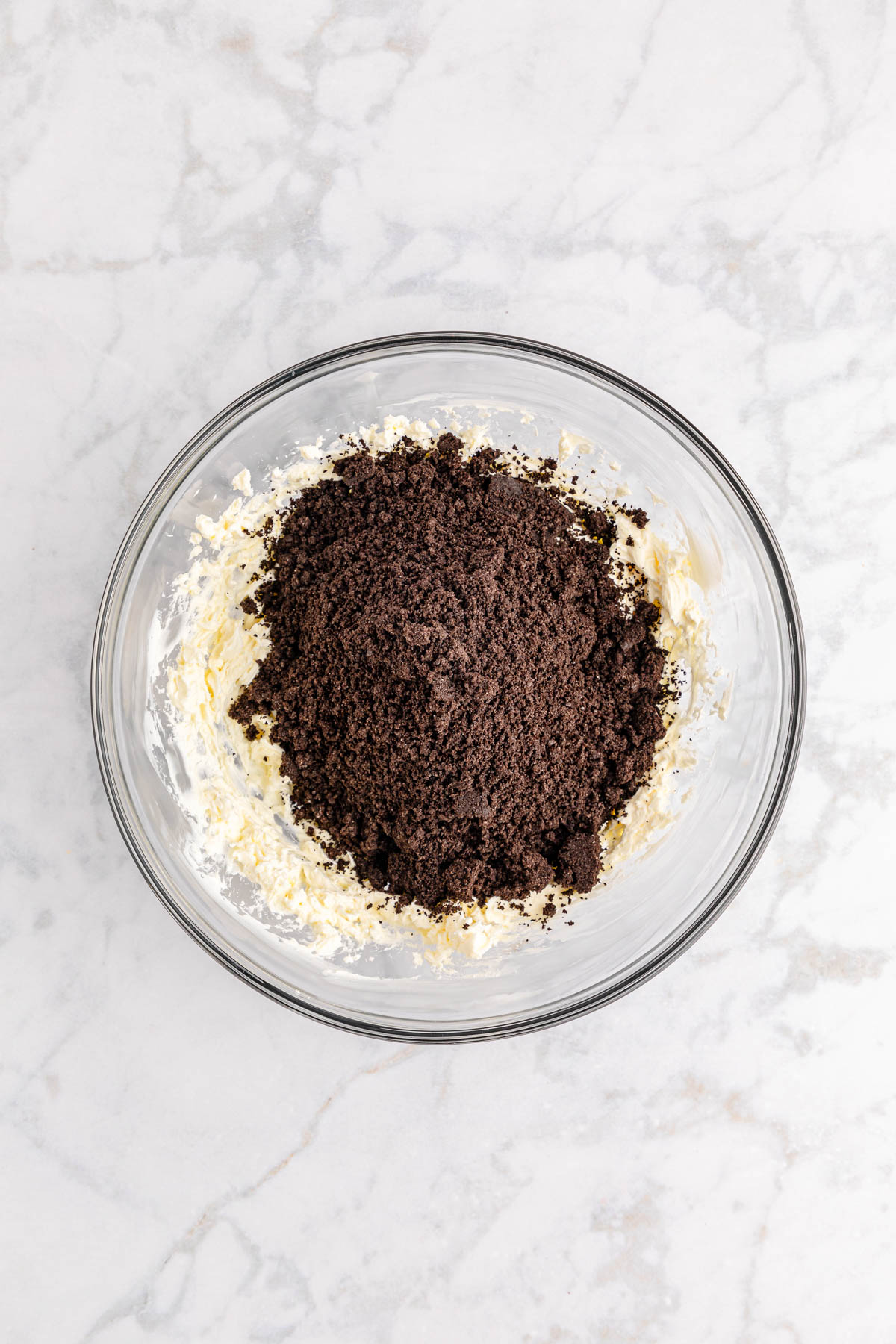 A glass bowl filled with a mixture of Oreo crumbs and cream cheese