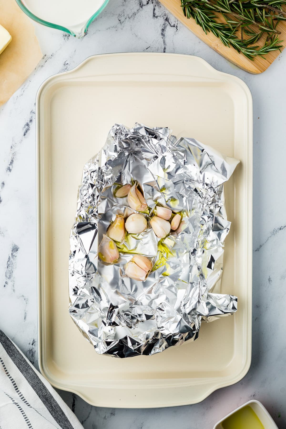 Foil with garlic and herbs on a marble countertop.