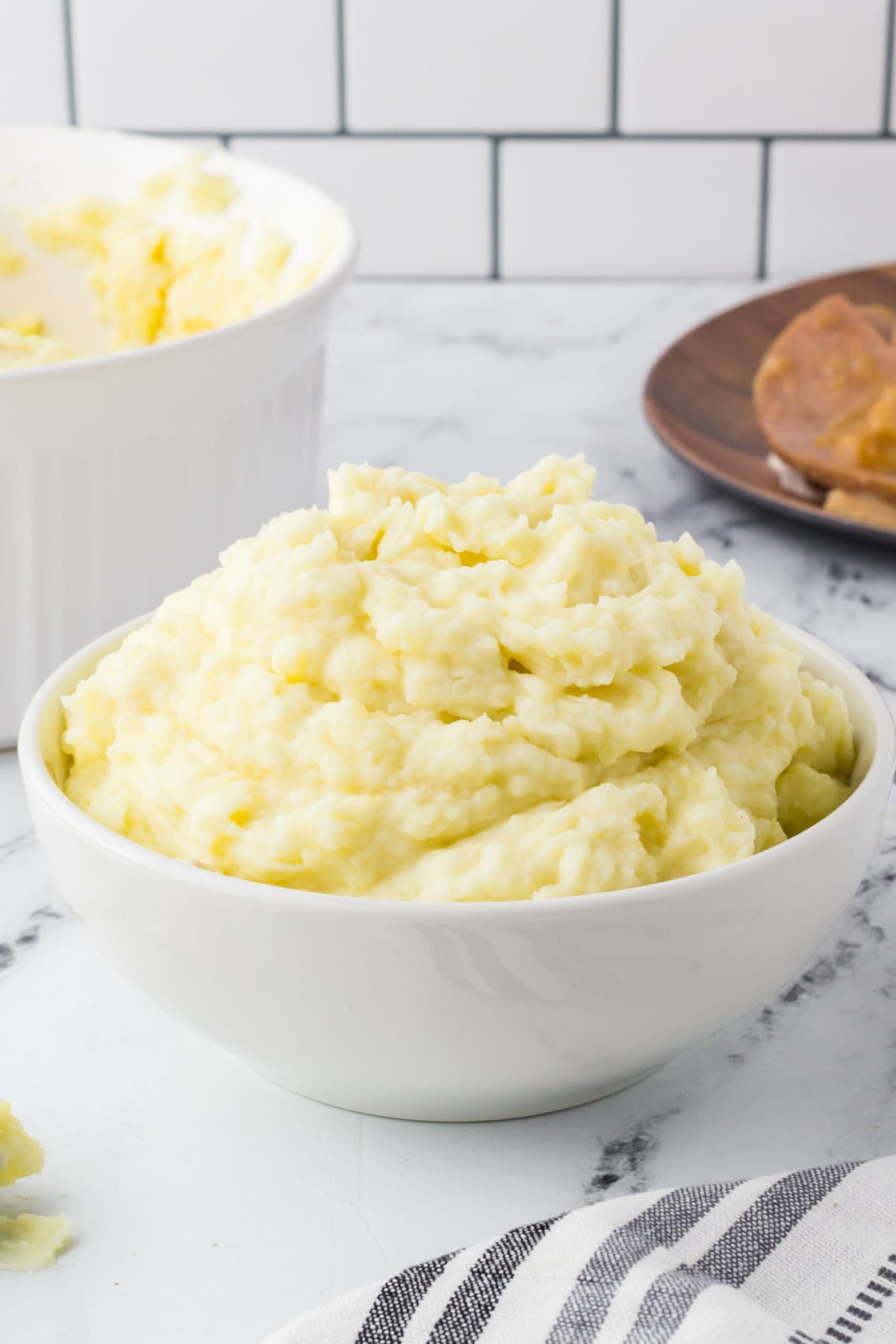 A bowl of mashed potatoes next to a bowl of mashed potatoes.