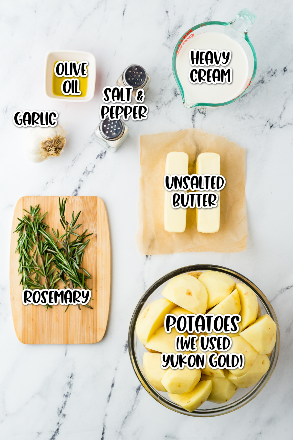 The ingredients for rosemary potatoes are shown on a marble cutting board.