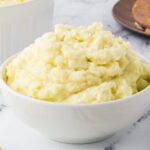 A bowl of mashed potatoes on a table.