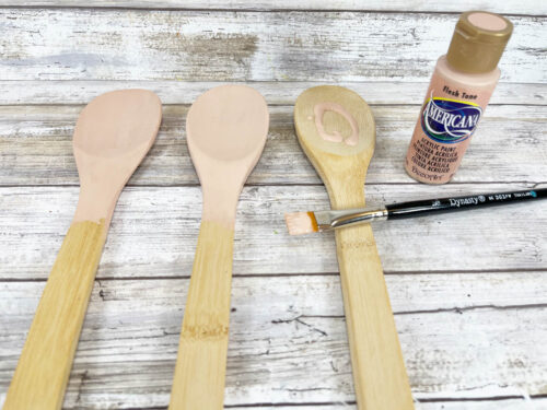 A set of wooden spoons with paint and paintbrushes.