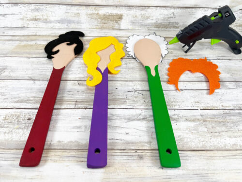 Three spoons with different hairstyles and a glue gun.