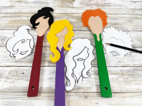 Three wooden spoons with different colored hair on them.