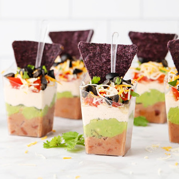 Game day favorite - Guacamole dip in plastic cups with tortilla chips.