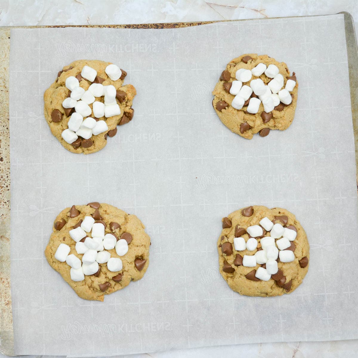 Four s'mores cookies on a baking sheet.