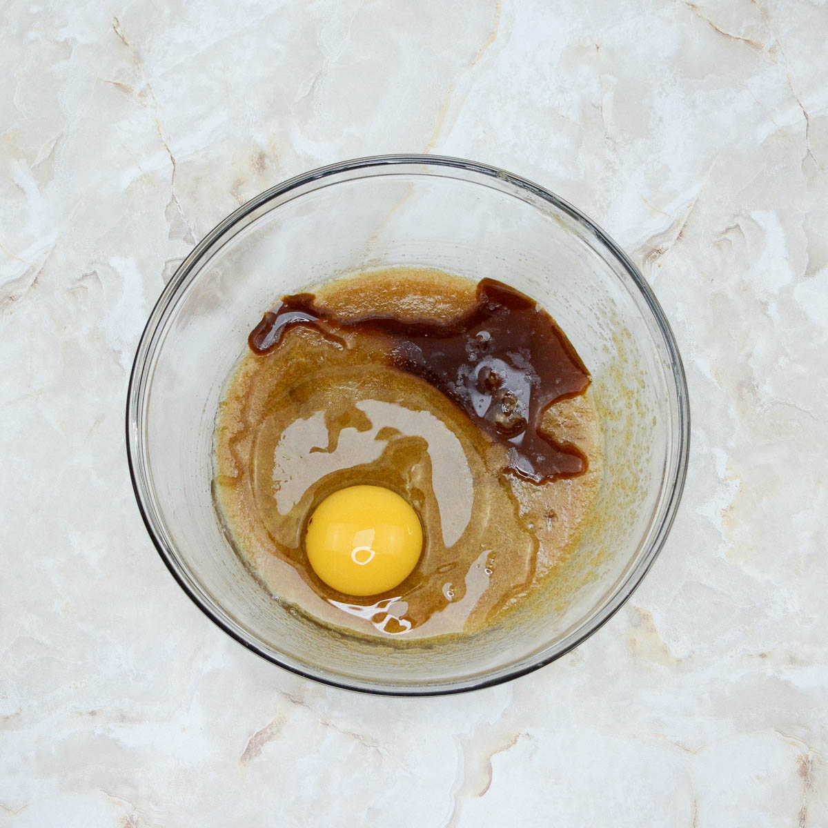A glass bowl with an egg and sugar mixture in it.