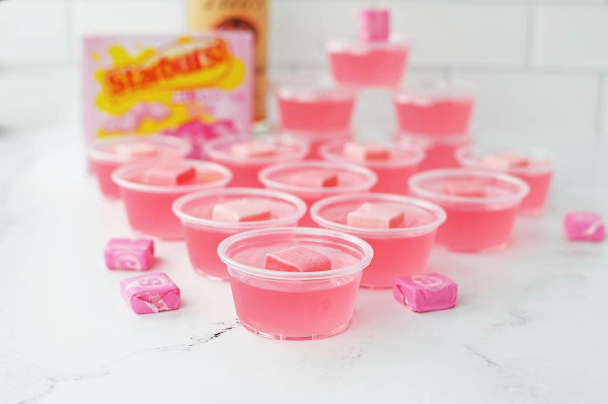 Pink jello shots on a white counter.