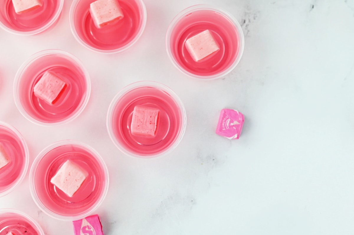 Pink starburst in plastic cups on a marble table.