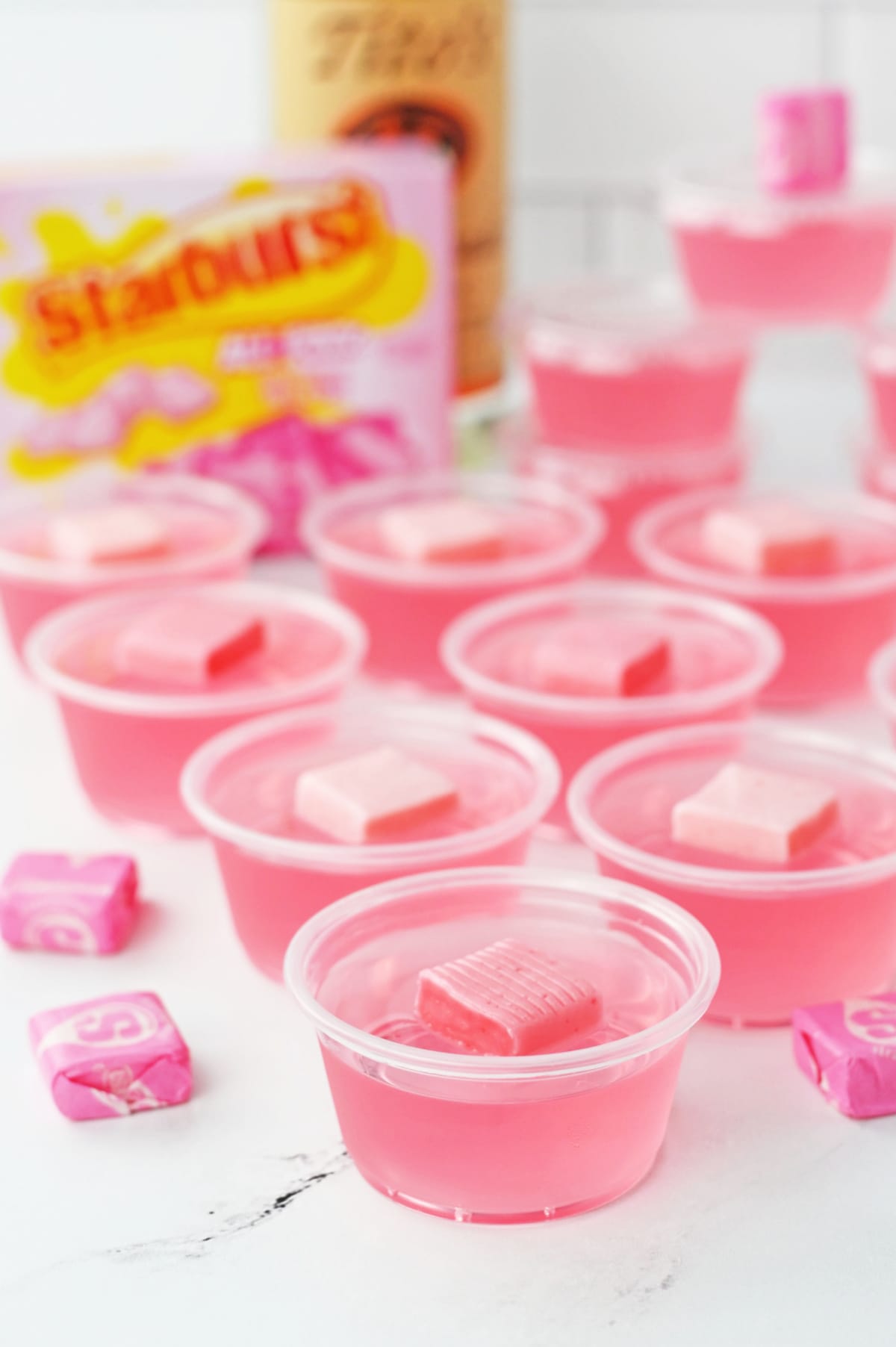 Pink starburst candy in plastic cups on a counter.