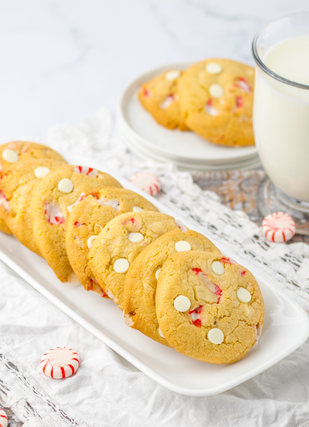 A plate of cookies with peppermint candies and a glass of milk.