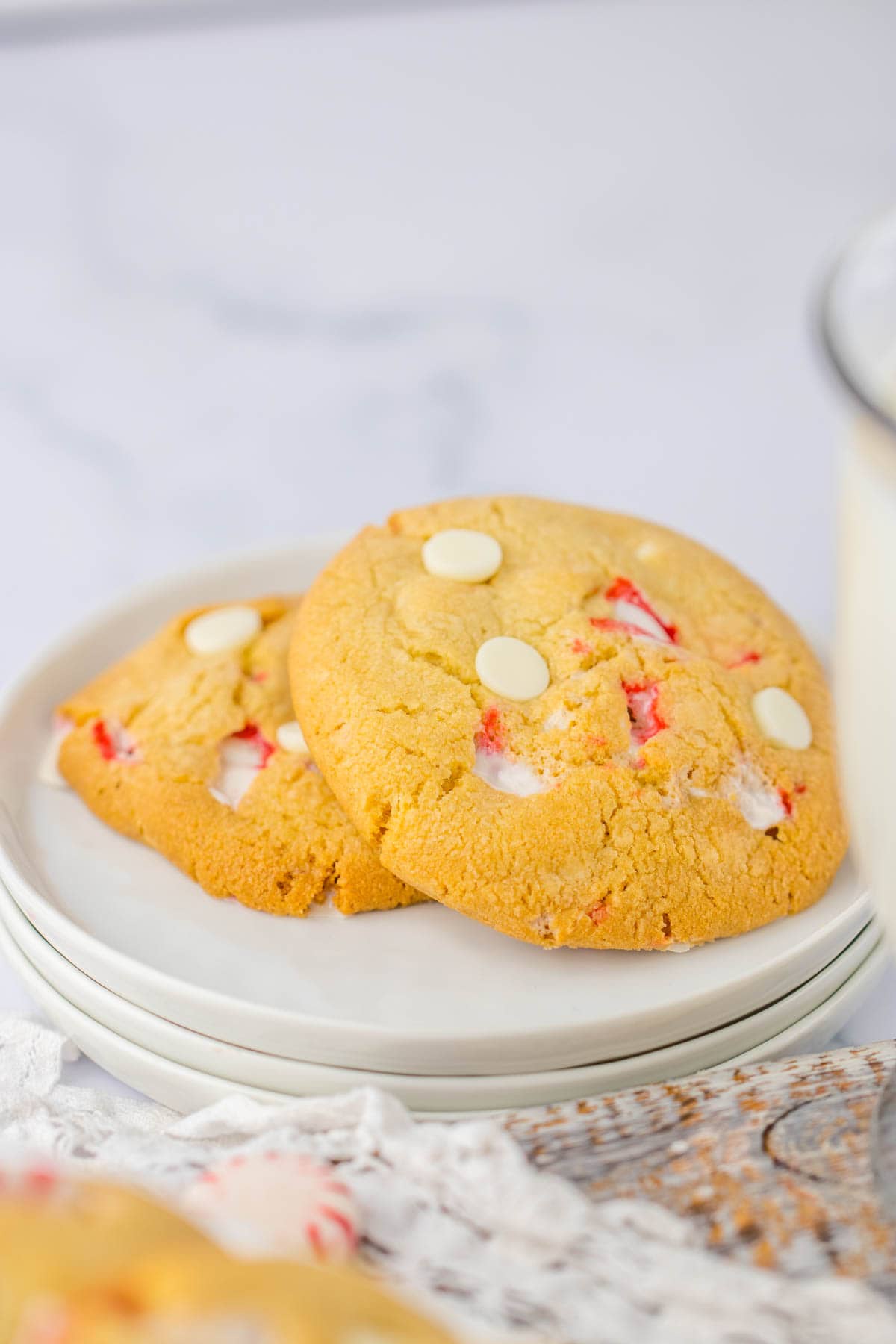 White chocolate peppermint cookies on a plate with a glass of milk.