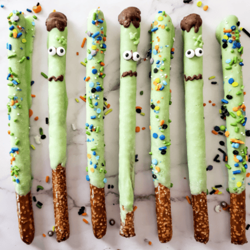 Zombie pretzel sticks with green frosting and sprinkles.