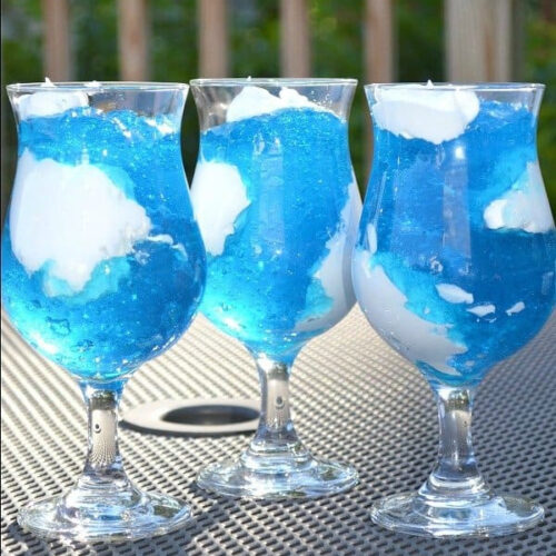 Three glasses of blue jello sitting on a table.