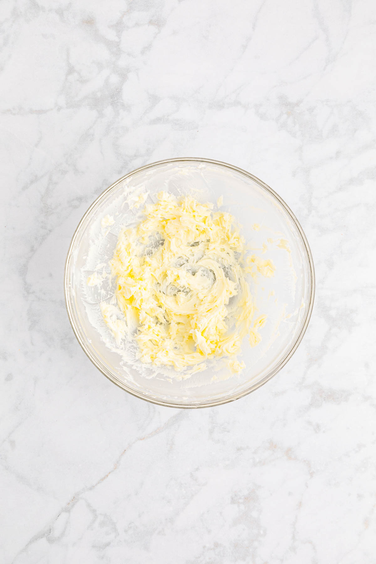 Butter in a glass bowl on a marble surface.