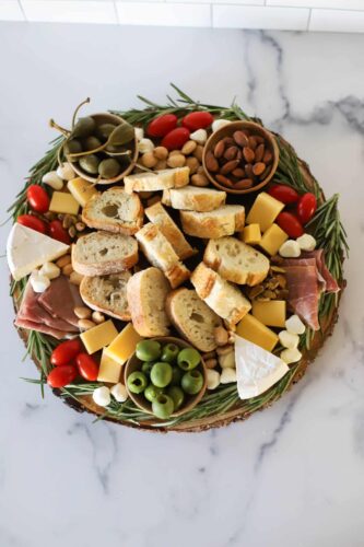 A festive Christmas charcuterie board showcasing an assortment of delectable meats and cheeses, elegantly presented on a sleek marble countertop.