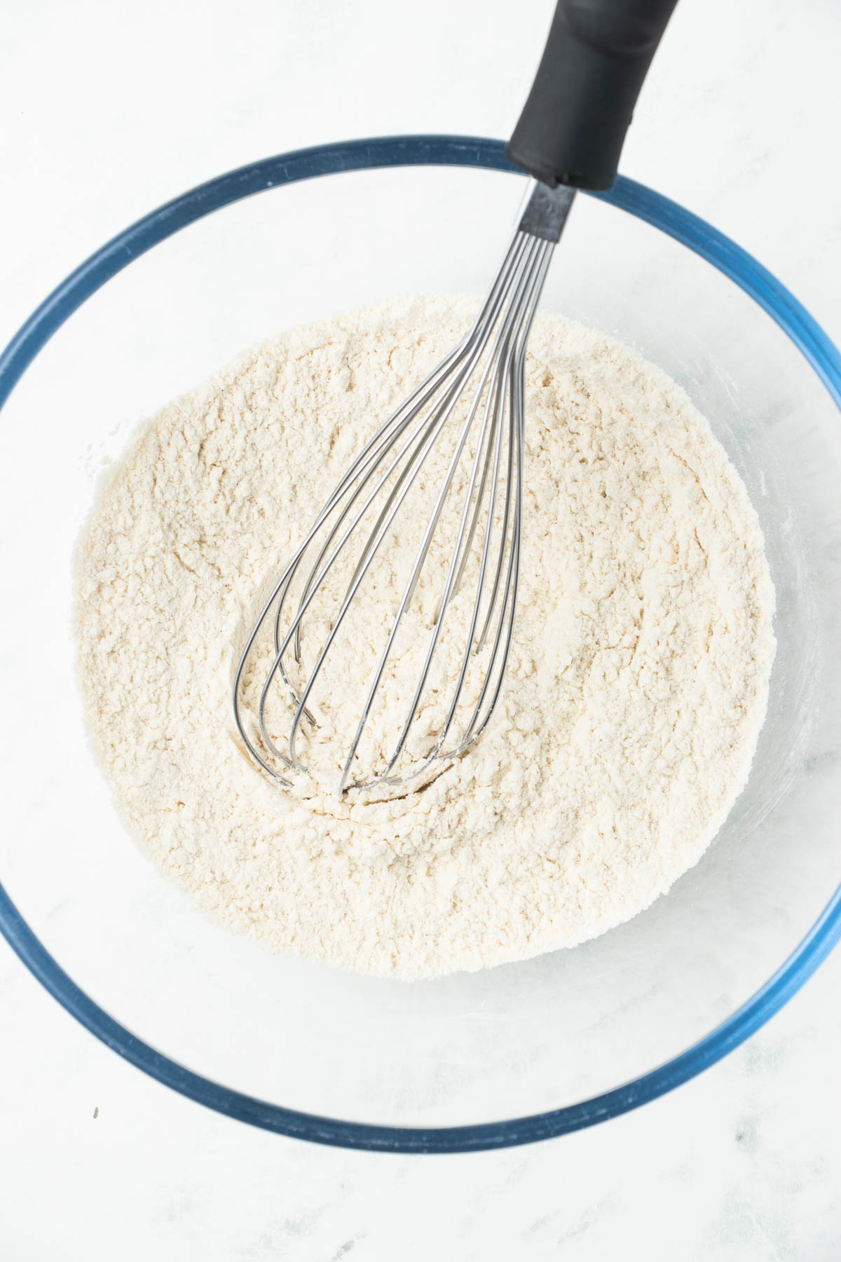 Whisking flour in a glass bowl.