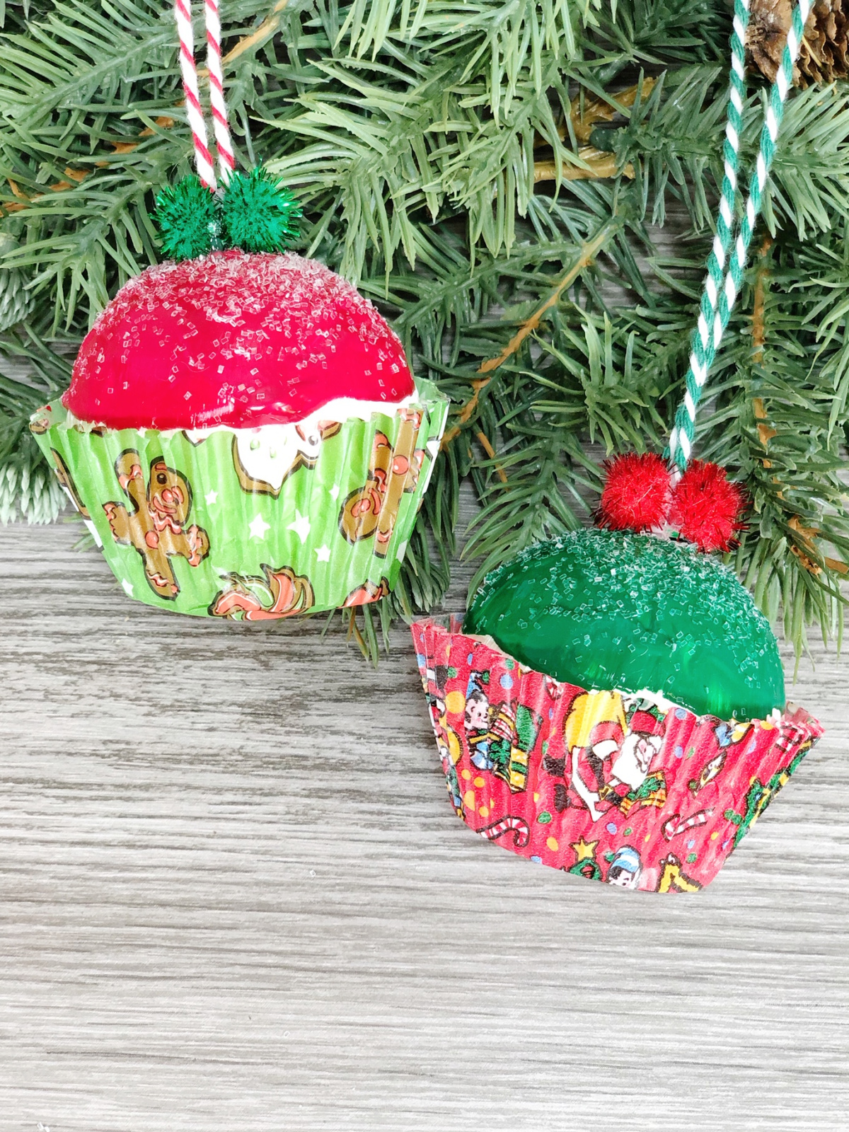 Cupcakes ornaments with a Christmas tree branch behind them