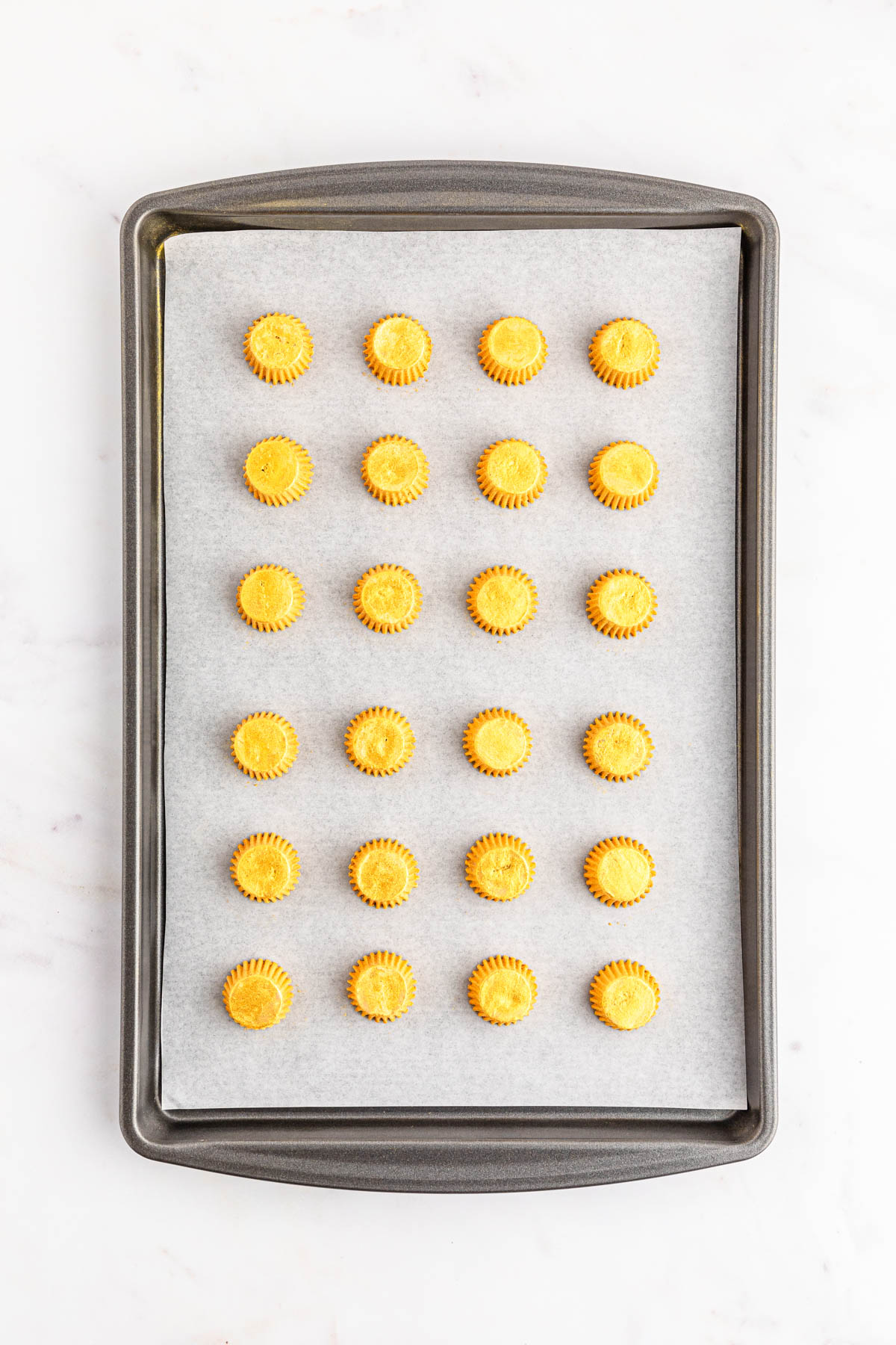 A baking sheet with yellow candies on it.