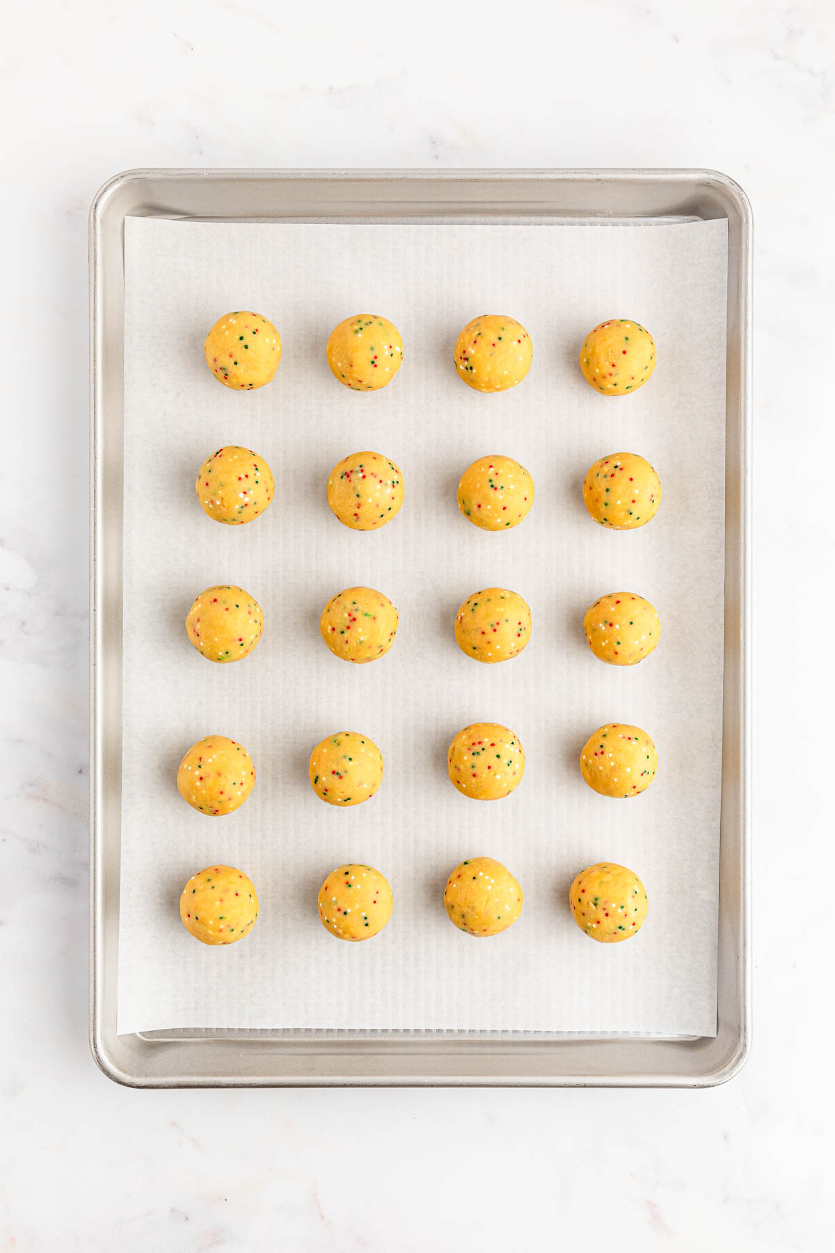 A baking sheet with yellow Oreo balls on it.