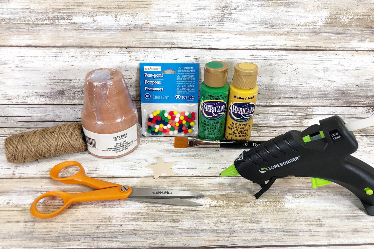 A glue gun, scissors, and other craft supplies are laid out on a wooden table.