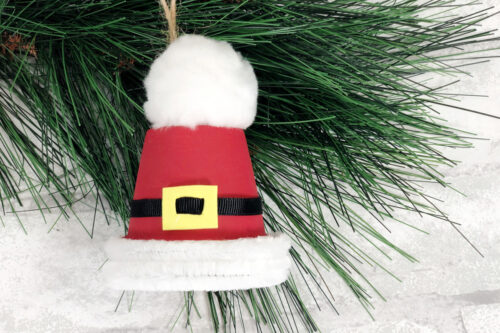 A santa claus ornament hanging on a christmas tree.