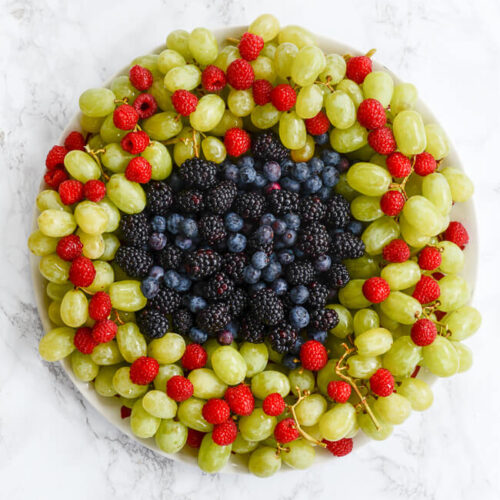 A plate filled with grapes and blackberries.