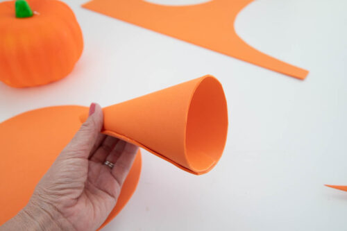 A person holding an orange paper cone on a table.