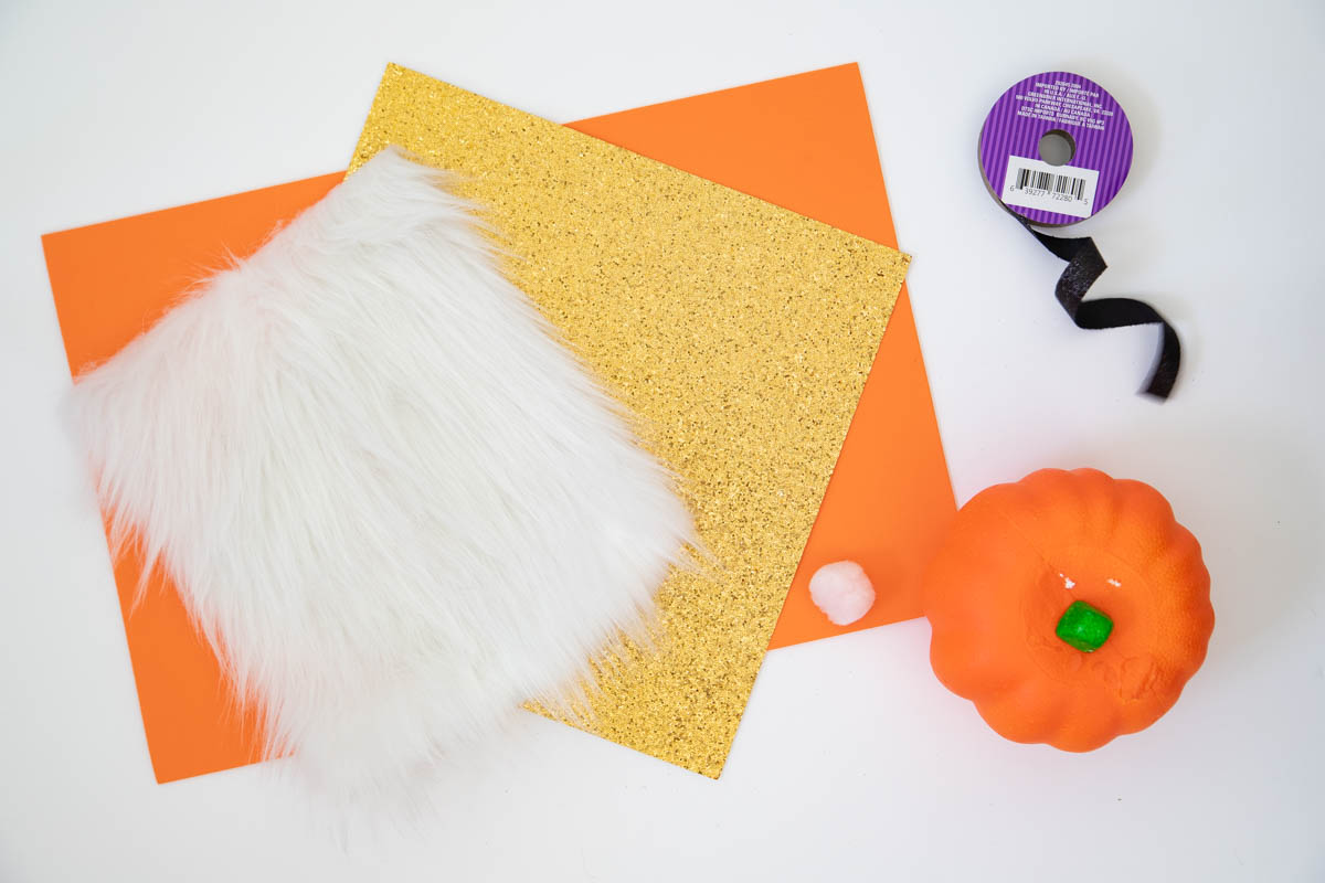 A pumpkin, orange paper, and a furry piece of fabric.