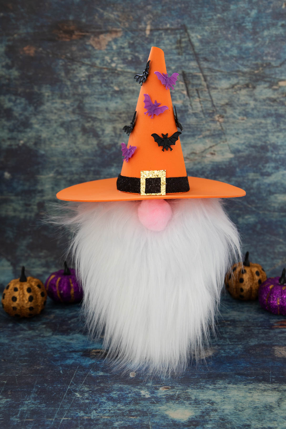 A gnome with an orange hat and pumpkins on a blue background.