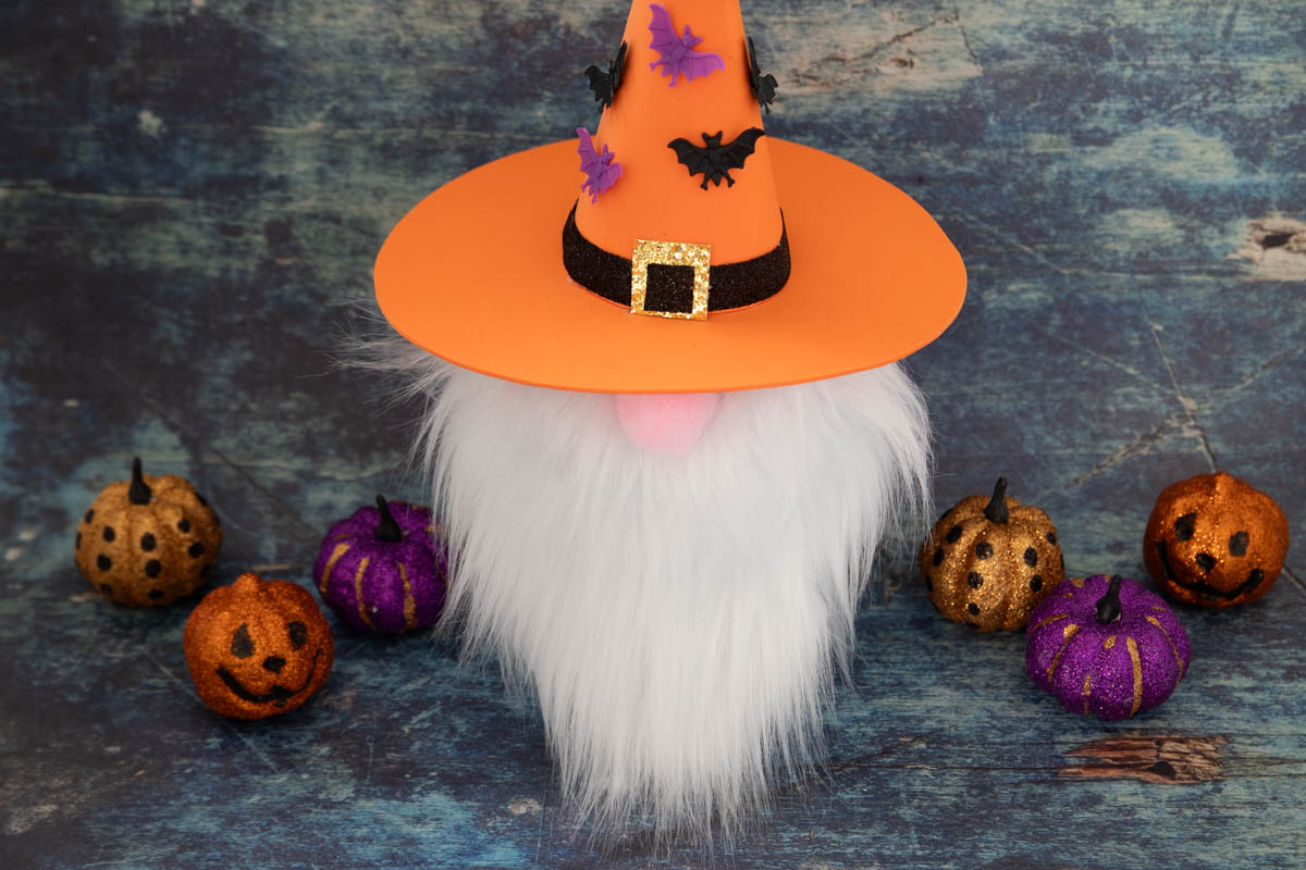 A gnome pumpkin with a hat and pumpkins on a table.