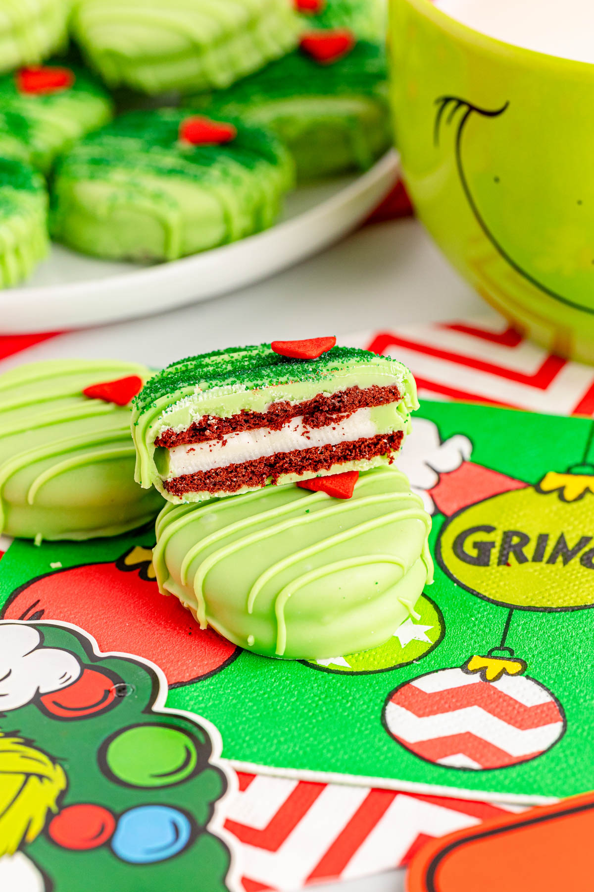 Grinch cookies on a table next to a mug