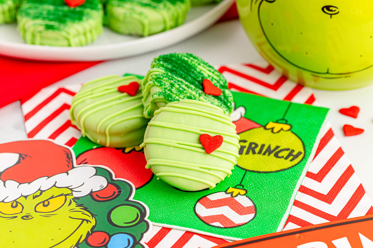 The grinch cookies are on a table next to a christmas card.