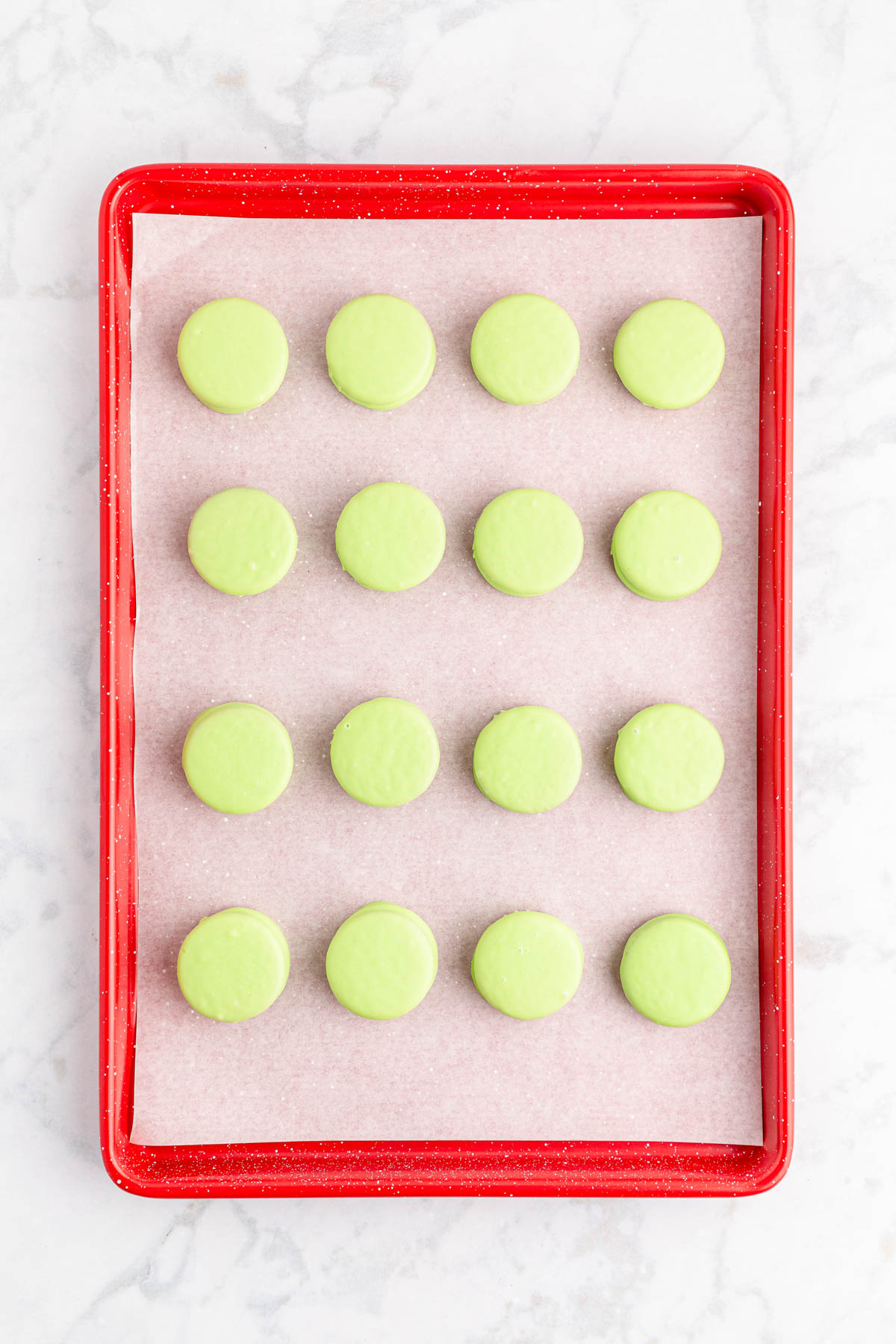 Green Oreos on a red baking sheet.