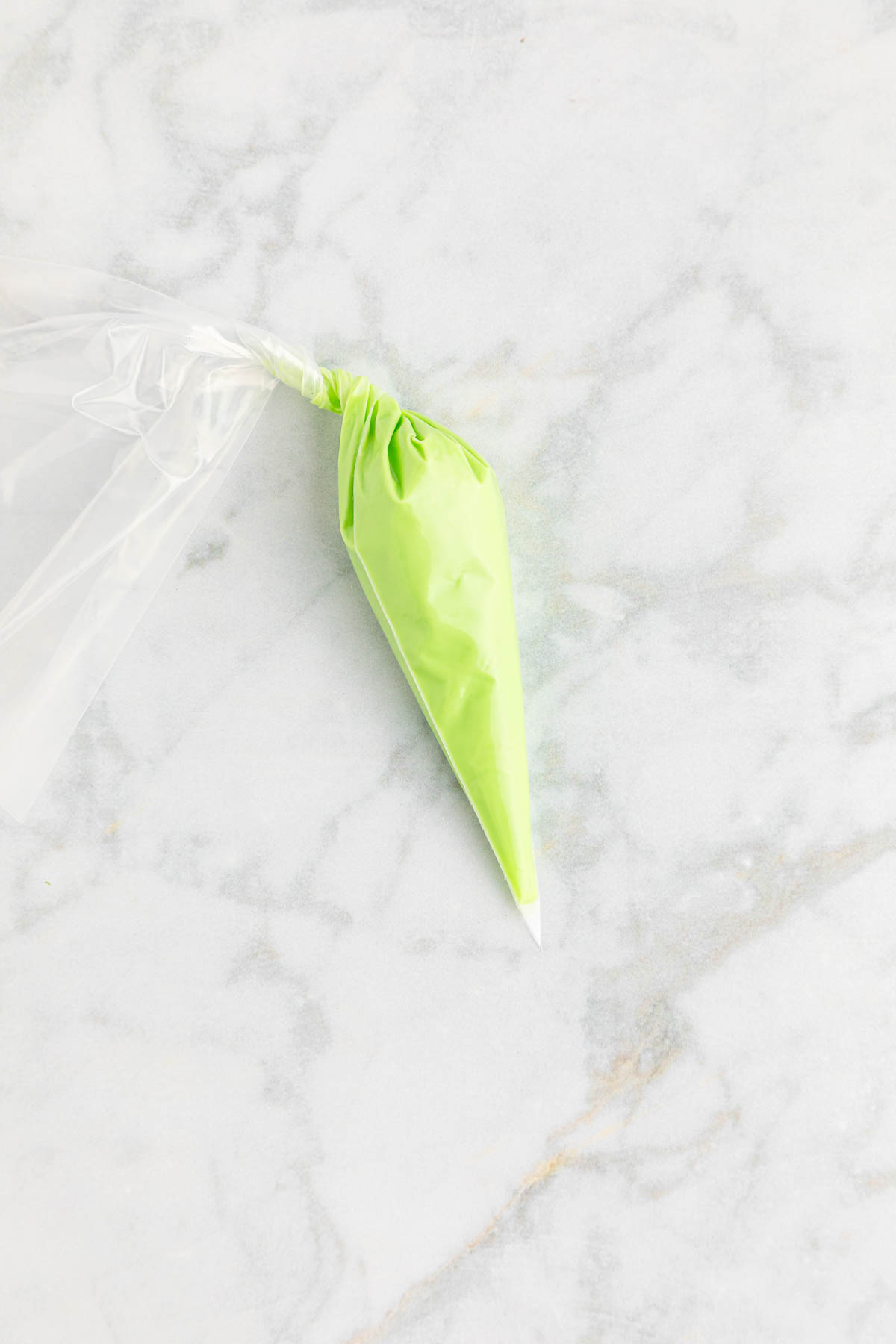 A green plastic piping bag on a marble surface.