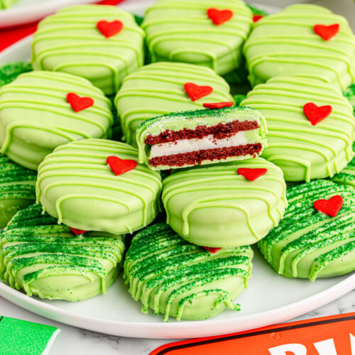 A plate of cookies with green frosting and red hearts.